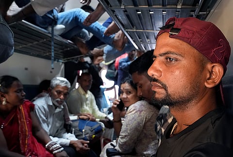 Dharmendar Kumar sits in the overcrowded general coach. Above him, others lie on luggage racks, a common sight on Indian trains where space is a luxury few can afford.