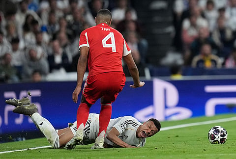 Real Madrid's Kylian Mbappe, bottom, is fouled by Bayern's Jonathan Tah during the Champions League quarterfinal first leg soccer match between Real Madrid and Bayern Munich in Madrid, Spain.