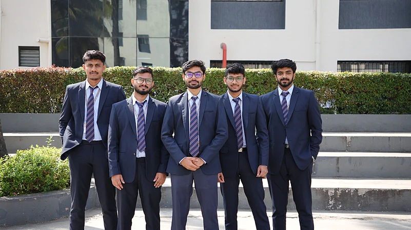 Five students in navy blue suits posing outdoors