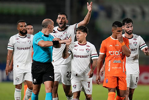 Yeferson Soteldo of Brazil's Fluminense, center, and Juan Freytes of Brazil's Fluminense (22) argue with referee Jose Burgos, of Uruguay, during a Copa Libertadores Group C soccer match against Venezuela's Deportivo La Guaira in Caracas, Venezuela.
