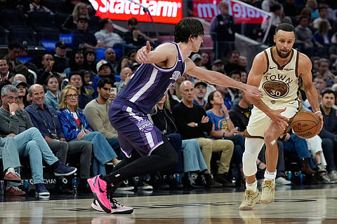 Golden State Warriors guard Stephen Curry (30) moves the ball while defended by Sacramento Kings center Maxime Raynaud (42) during the second half of an NBA basketball game in San Francisco.