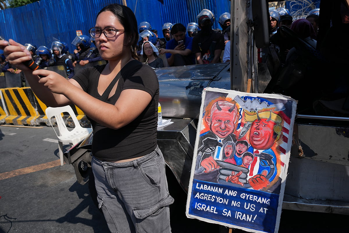 A protester stands beside a caricature of Israel Prime Minister Benjamin Netanyahu and U.S. President Donald Trump during a rally by transport workers and activists protesting the rise in oil prices on Friday, March 27, 2026, near the Malacanang presidential palace in Manila, Philippines. - Aaron Favila