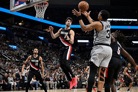 San Antonio Spurs forward Keldon Johnson (3) grabs the rebound ahead of Portland Trail Blazers' Jrue Holiday (5) and Deni Avdija (8) during the second half of an NBA basketball game in San Antonio.