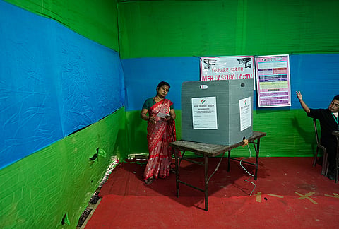 A polling official, right, instructs a woman to leave after she cast her vote at a polling center during the Assam state election in Guwahati.