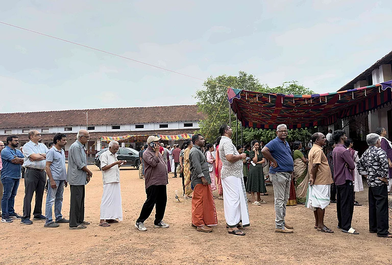 People queue up to vote outside a polling booth during the Kerala state election in Kochi. - | Photo: AP/ R S Iyer