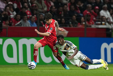 Emiro Garces of the United States' LA Galaxy, right, and Jesus Angulo of Mexico's Toluca vie for the ball during a CONCACAF Champions Cup quarterfinal first leg soccer match in Toluca, Mexico.