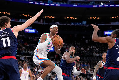 Oklahoma City Thunder guard Shai Gilgeous-Alexander, second from left, passes as Los Angeles Clippers center Brook Lopez, left, guard Kris Dunn, center, forward John Collins, second from right, and forward Kawhi Leonard defend during the first half of an NBA basketball game in Inglewood, California.