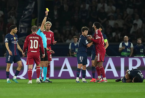 Referee Jose Maria Sanchez shows a yellow card to Liverpool's Joe Gomez during the Champions League quarterfinal first leg soccer match between Paris Saint-Germain and Liverpool in Paris.