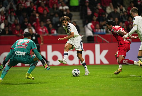 Julian Aude, center, passes the ball to Marco Reus of the United States' LA Galaxy to score against Mexico's Toluca during a CONCACAF Champions Cup quarterfinal first leg soccer match in Toluca, Mexico.