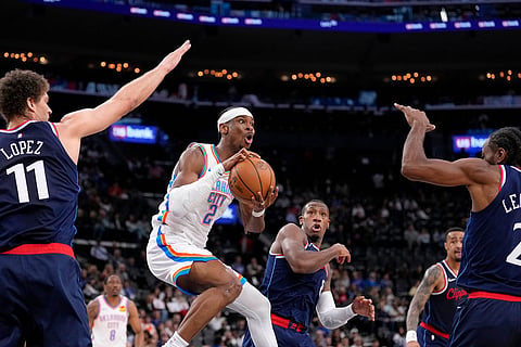 Oklahoma City Thunder guard Shai Gilgeous-Alexander, second from left, passes as Los Angeles Clippers center Brook Lopez, left, guard Kris Dunn, center, forward John Collins, second from right, and forward Kawhi Leonard defend during the first half of an NBA basketball game in Inglewood, Calif.