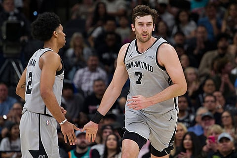 San Antonio Spurs center Luke Kornet (7) celebrates a basket with teammate Dylan Harper during the first half of their NBA basketball game against the Portland Trail Blazers in San Antonio.