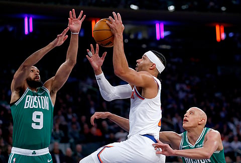 New York Knicks guard Josh Hart, middle, shoots over Boston Celtics guard Derrick White, left, and forward Jordan Walsh during the first half of an NBA basketball game in New York.