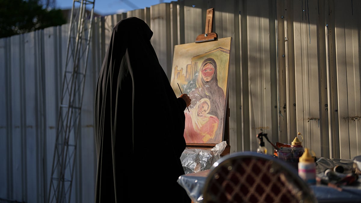 A woman paints a canvas at the site of a concert honoring children killed in a strike on a school in Minab, southern Iran, outside a theater hall in Tehran, Iran, Monday, April 6, 2026.  - Francisco Seco