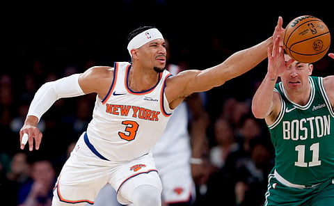 New York Knicks guard Josh Hart, left, and Boston Celtics guard Payton Pritchard, right, battle for the ball during the first half of an NBA basketball game in New York.