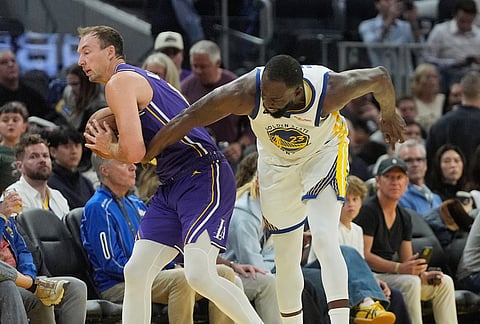 Los Angeles Lakers guard Luke Kennard, left, holds on to the ball while being defended by Golden State Warriors forward Draymond Green during the second half of an NBA basketball game in San Francisco.
