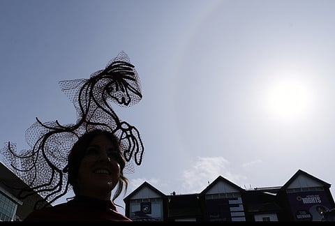 A racegoer is silhouetted as she attends Ladies Day, the second day of the Grand National Horse Racing festival, at Aintree racecourse, near Liverpool, England.