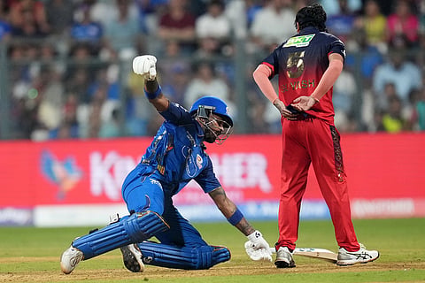 Mumbai Indians' captain Hardik Pandya dives on the pitch to avoid a run out as Royal Challengers Bengaluru's Suyash Sharma looks on during the Indian Premier League cricket match between Mumbai Indians and Royal Challengers Bengaluru, in Mumbai, India.