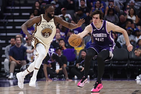 Golden State Warriors forward Draymond Green (23) and Sacramento Kings center Maxime Raynaud (42) attempt to grab the loose ball during the second half of an NBA basketball game in Sacramento, Calif.