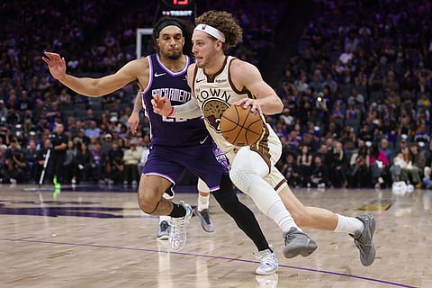 Golden State Warriors guard Brandin Podziemski (2) dribbles past Sacramento Kings guard Devin Carter, behind, during the second half of an NBA basketball game in Sacramento, Calif.