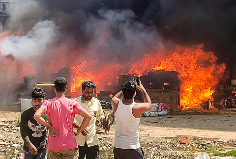 Flames engulf shanties as people look on after a fire broke out in a slum cluster in Sector 51, Gurugram. Fire tenders were rushed to the spot to douse the blaze, which spread rapidly through the densely packed area. 