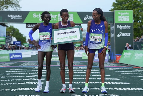 From left, Kenya's Magdalyne Masai, Ethiopia's Shure Demise and Ethiopia's Misgane Alemayehu pose after crossing the finish line of the women's race of the Paris marathon, in Paris.