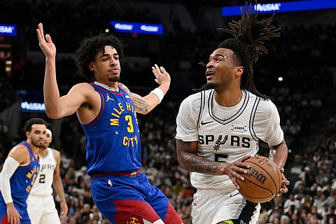 San Antonio Spurs guard Stephon Castle (5) drives against Denver Nuggets guard Julian Strawther during the first half of an NBA basketball game in San Antonio.
