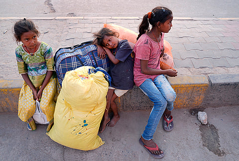 Exhausted and Tired: Nandini, Kamal and Priyanka (from right) rest by the roadside with their heavy bags, waiting for their mother who's gone to fetch tickets for the family. 
