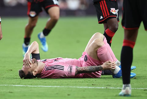 Inter Miami forward Lionel Messi grabs his ankle after being tripped in the second half of an MLS soccer match against the New York Red Bulls, in Miami.