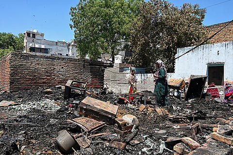 Women look for their belongings amidst charred remains after a fire broke out at a slum area of Rohini, in New Delhi.
