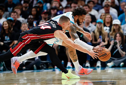 Charlotte Hornets forward Miles Bridges, back, and Miami Heat guard Tyler Herro (14) battle for a loose ball during the first half of an NBA play-in tournament basketball game in Charlotte, North Carolina.