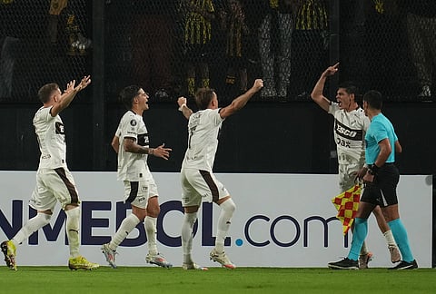 Franco Zapiola, right, of Argentina's Platense celebrates with teammates after scoring his side's second goal, from the penalty spot, during a Copa Libertadores Group E soccer match against Uruguay's Peñarol in Montevideo, Uruguay.