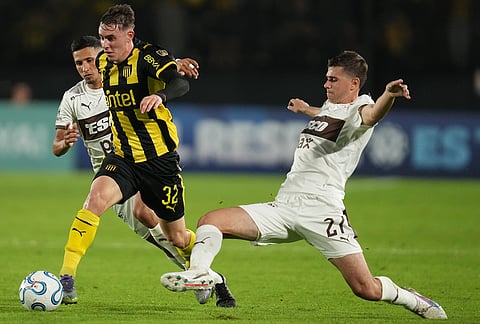 Leandro Umpierrez of Uruguay's Peñarol, left, carries the ball past Santiago Dalmasso of Argentina's Platense during a Copa Libertadores Group E soccer match in Montevideo, Uruguay.