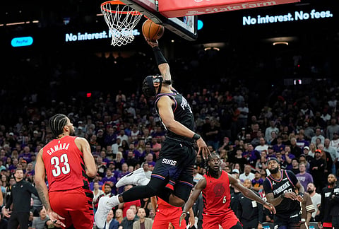 Phoenix Suns guard Jordan Goodwin, center, scores as Portland Trail Blazers forward Toumani Camara (33), Trail Blazers guard Jrue Holiday (5) and Suns forward Royce O'Neale, right, look on during the second half of an NBA play-in tournament basketball game, in Phoenix.