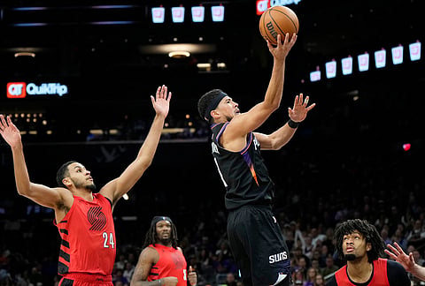 Phoenix Suns guard Devin Booker (1) drives past Portland Trail Blazers forward Kris Murray (24) as Trail Blazers center Robert Williams III and Portland Trail Blazers guard Shaedon Sharpe, right, look on during the second half of an NBA play-in tournament basketball game, in Phoenix. 