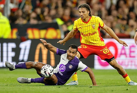 Toulouse's Cristian Casseres Jr, down, and Lens' Ismaelo Ganiou fight for the ball during a League One soccer match between Lens and Toulouse in Lens, France.