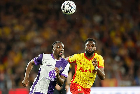 Toulouse's Seny Koumbassa, left, and Lens' Odsonne Edouard run for the ball during a League One soccer match between Lens and Toulouse in Lens, France.