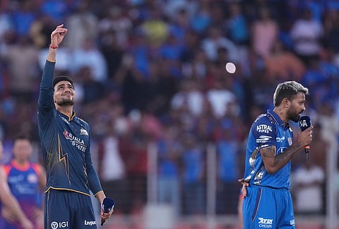 Gujarat Titans' captain Shubman Gill, left, toss the coin as Mumbai Indians' captain Hardik Pandya looks on before the start the Indian Premier League cricket match between Gujarat Titans and Mumbai Indians in Ahmedabad.