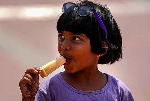 A child eats an ice cream to beat the heat on a hot summer day amid scorching temperatures, in New Delhi.
