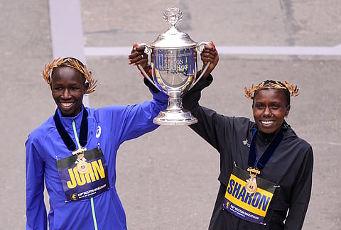 Boston Marathon winner John Korir of Kenya, left, hoists the trophy with women's division winner Sharon Lokedi also of Kenya, at the finish line of the Boston Marathon in Boston.
