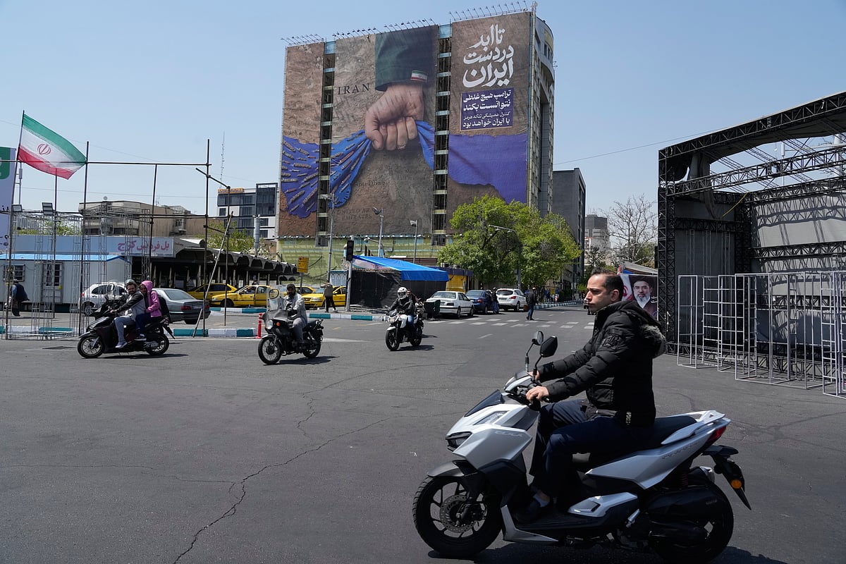 AP  : Motorbikes drive past a billboard that shows a graphic depicting a military personnel's hand holding the Strait of Hormuz in his fist with signs which read in Farsi: "In Iran's hands forever," "Trump couldn't do a damn thing," "The control of Strait of Hormuz will be Iran's forever," in Vanak Square in northern Tehran, Iran, Thursday, April 16, 2026. 