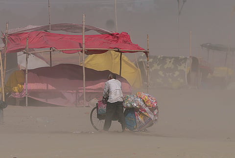 A cyclist moves through dust near Sangam on a hot summer day, in Prayagraj, Uttar Pradesh.