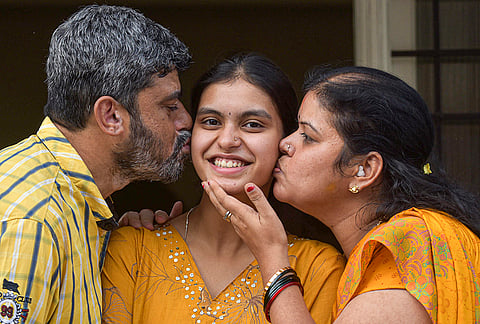 SSLC topper Brindha M Thapsey, centre, who scored 625/625, celebrates with her parents at their residence, in Chikkamagaluru, Karnataka.