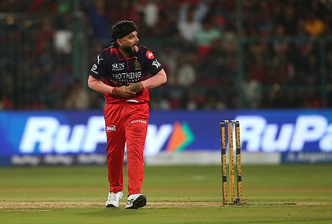 Royal Challengers Bengaluru's Suyash Sharma holds his wrist after getting injured while fielding during the Indian Premier League cricket match between Royal Challengers Bengaluru and Gujarat Titans in Bengaluru.