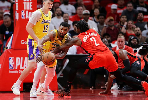 Houston Rockets forward Dorian Finney-Smith (2) knocks away the ball from Los Angeles Lakers guard Marcus Smart, center, as forward Jake LaRavia (12) looks on during the first half in Game 3 of a first-round NBA playoffs basketball series in Houston.