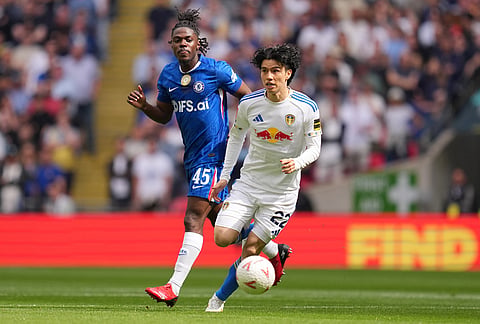 Leeds' Ao Tanaka in action in front of Chelsea's Romeo Lavia during the FA Cup semifinal soccer match between Chelsea and Leeds in London, England.
