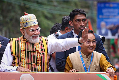 Prime Minister Narendra Modi waves during a roadshow, in Gangtok, Sikkim. State Chief Minister Prem Singh Tamang is also seen. 
