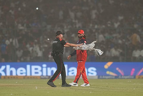 Royal Challengers Bengaluru's captain Rajat Patidar reacts amid a dust storm during the Indian Premier League (IPL) T20 cricket match between Delhi Capitals and Royal Challengers Bengaluru, in New Delhi.