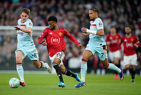 Manchester United's Amad Diallo in action between Brentford's Yehor Yarmolyuk, left, and Kevin Schade during the Premier League soccer match between Manchester United and Brentford in Manchester, England.