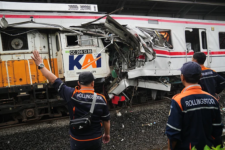 Workers examine the wreckages of trains after a collision in Bekasi, Indonesia - AP