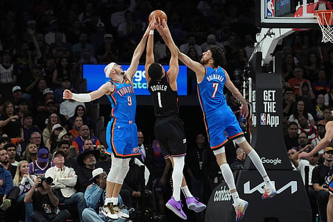 Phoenix Suns guard Devin Booker (1) battles with Oklahoma City Thunder guard Alex Caruso (9) and Thunder center Chet Holmgren (7) for a rebound during the second half of Game 4 in a first-round NBA playoffs basketball series in Phoenix.